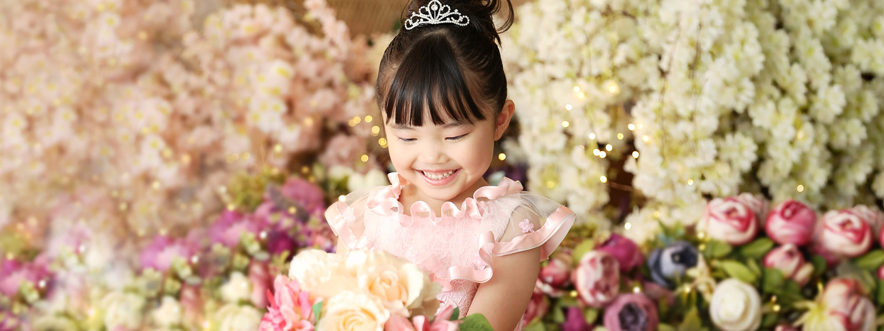 ピンクのドレスを着た女の子が花束を抱えている様子