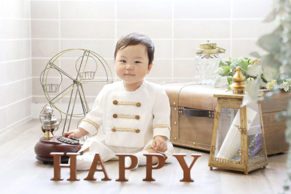 男の子がHAPPYと書いた置物の後ろに座っている様子