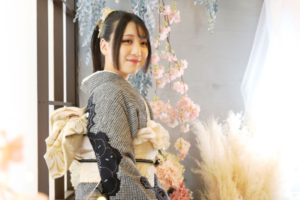 成人式の袴を着て、カラフルな花の前でほほ笑む女性
