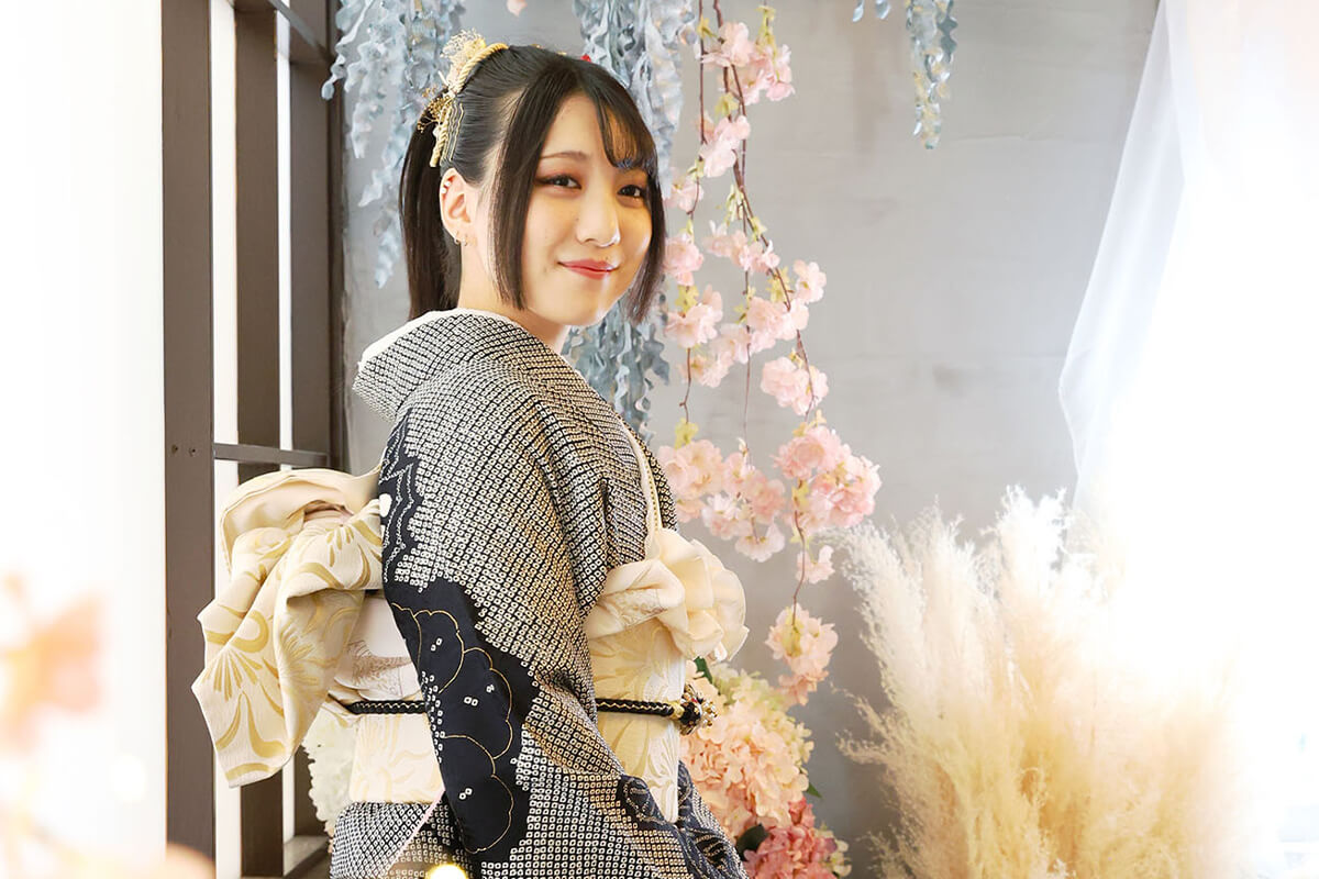 成人式の袴を着て、カラフルな花の前でほほ笑む女性